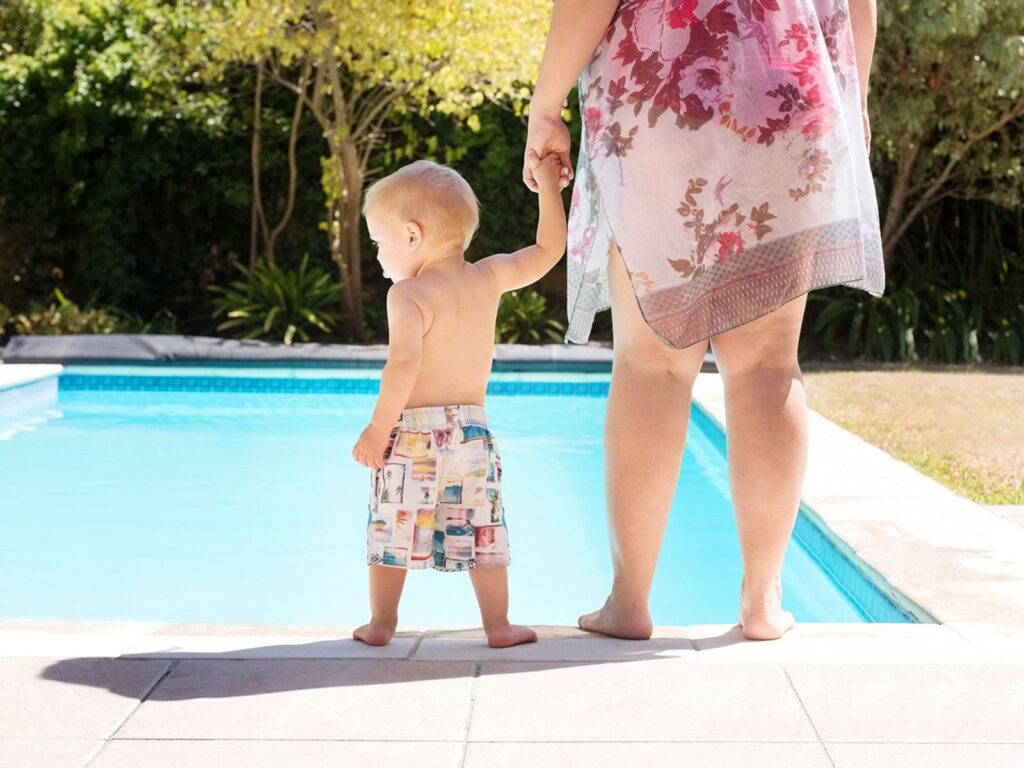 Toddler standing near swimming pool 